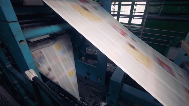 Fresh daily newspapers rolling on a printing equipment. 4K.