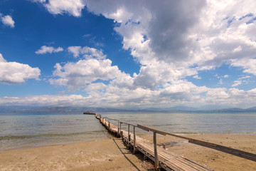 Wooden pier on Apraos beach near Kassiopi town with perfect views of the Albanian mountains. Corfu island. Greece.