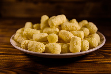 Ceramic plate with corn sticks on wooden table
