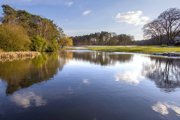 Lake water reflections with dark blue sky and fluffy clouds