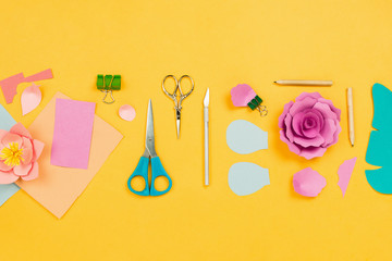 Flatlay with papercraft flowers, cardboard, paper, stationary and art accessories, concept of education, creativity or hobby