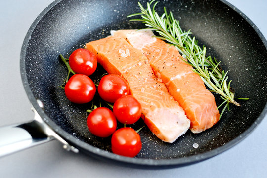 Salmon Trout Fillet on Pan Cooking Raw Fish Pepper Salt Rosemary Tomato Cherry Lemon Lifestyle Healthy Concept