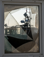 Looking through a battered windowpane at a fishing boat. Focus on the boat Concept: vacation and travel or crime