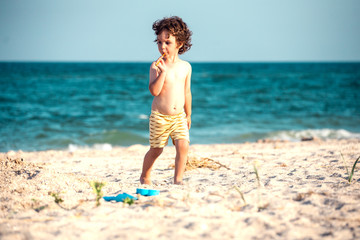 The boy walks along the sandy beach.