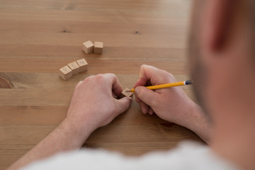 Craftsman labels wooden cube with pencil