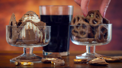 Sweet and salty chocolate covered salt and vingear potato chips and pretzels with cola drink, on rustic wood background.