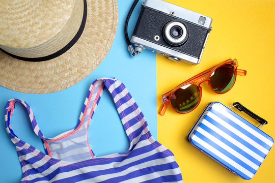 Summer holiday concept, Travel Concept with bag, camera and hat on blue and yellow background. Flat lay