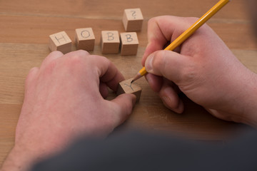 Craftsman labels wooden cube with pencil