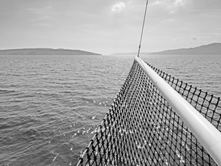 Kroatische Inseln im Meer mit Bug eines Segelschiffs im Vordergrund in schwarzweiß