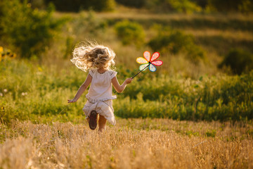 Cute little girl playing in the summer field of wheat