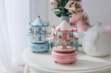 Children's toy carousel with small white horses in the bright space of the children's room