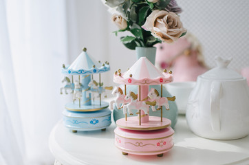 Children's toy carousel with small white horses in the bright space of the children's room