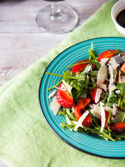Salad with strawberries, arugula and parmesan drizzled with balsamic glaze