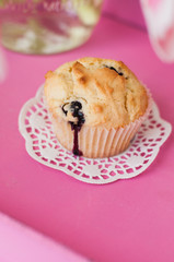 Freshly baked blueberry muffin or cupcake on paper doily on pink tray with tulip for mother's day, a birthday party or tea time