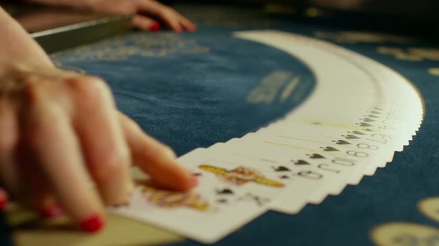 Casino croupier girl shuffles the poker cards and performing trick with cards. 