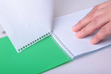 hands wresting the sheet of paper out of a spiral notebook.