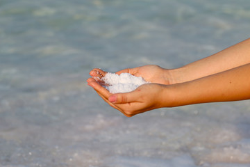 Fototapeta na wymiar Dead Sea, in the hands of a girl salt sea spa