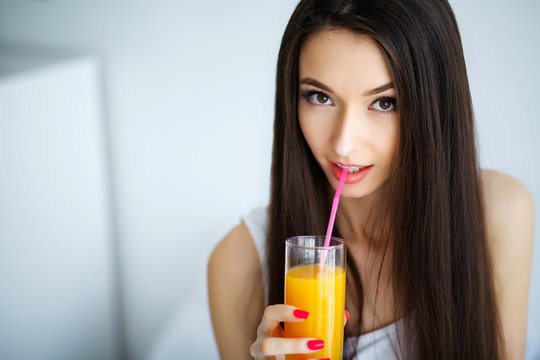 Casual smiling woman holding a glass of orange juice