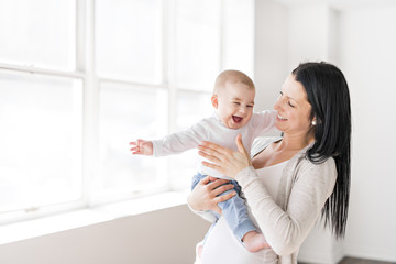 Mother holds baby on a beautiful room with white window