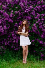 Happy beautiful young woman with long hair in a blooming spring Park, the charming girl in a white...