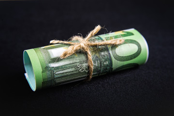 One hundred euro banknote tied up with a rope on black background