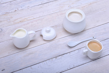 Cup of hot coffee espresso, coffee beans, jug of milk, and bowl with sugar on white background for copy space. Coffee concept.