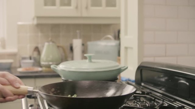 Man Frying Fresh Beans In Wok On Stove At Kitchen