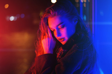 Sexy young woman posing over night city dramatic neon background