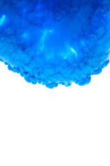 Color drop in water, photographed in motion. Abstract swirling. Cloud of silky bulb under water isolated on white background. Blue paint