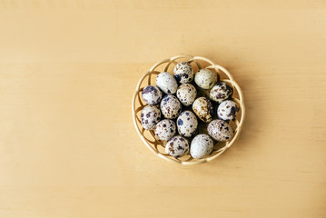  quail eggs in the straw plate on the wooden table