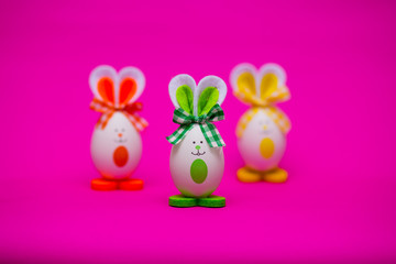 Multicolored funny eggs in the form of cute bunny on pink background. Happy easter. Festive decoration