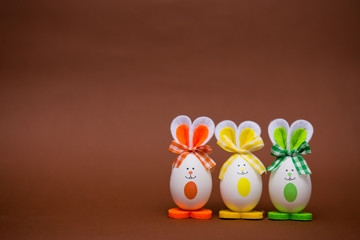 Multicolored funny eggs in the form of cute bunny on brown background. Happy easter. Festive decoration