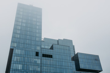Obraz premium Tower of modern skyscraper glass building in fog or mist