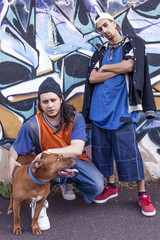 two rap singers with a dog in a subway with graffiti in the background