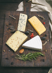 pieces of different cheeses on a brown wooden board