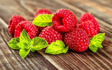 Ripe fresh raspberries with leaves on a wooden background