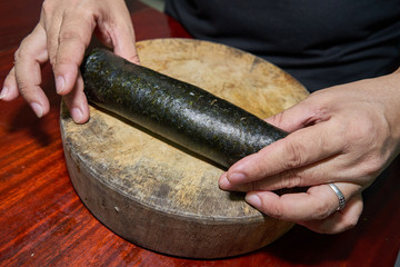 Woman hands to handle pork marinated tofu wrapped eggs on kelp on a wooden cutting board on a wooden table
