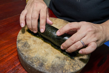 Woman hands to handle pork marinated tofu wrapped eggs on kelp on a wooden cutting board on a wooden table