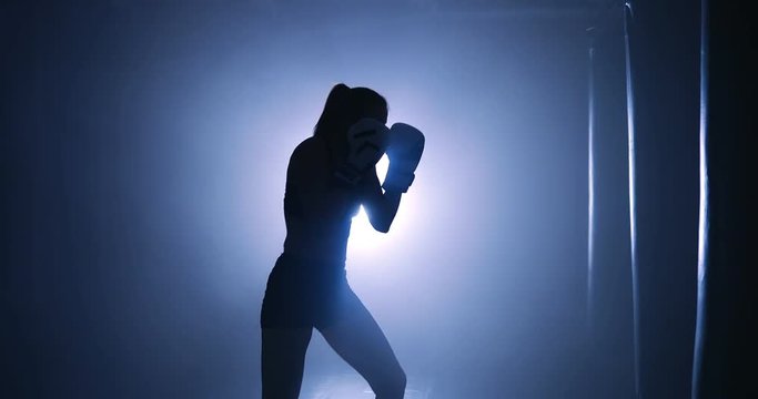 Girl boxer workout in a boxing club. Silhouette