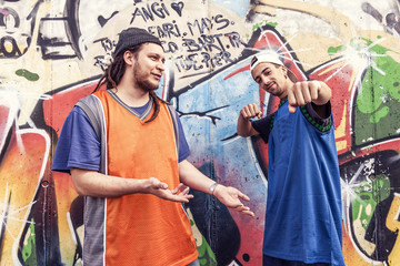 two rap singers in a subway with graffiti in the background