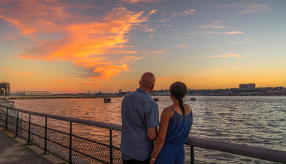 Fototapeta premium Couple watching beautiful sunset at riverside park, Manhattan NY