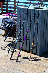 Fishing poles and reels propped up on a fish cleaning bin on a fishing pier in Dania Beach,Florida
