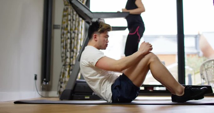 4K Fit attractive Asian couple working out together in home gym. Slow motion.