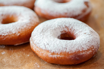 donuts sprinkled with sugar powder close-up on baking paper shallow focus
