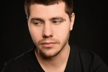 Obraz premium Young man with pierced eyebrow on black background