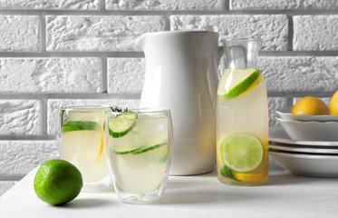 Glasses and bottle of fresh lemonade on table