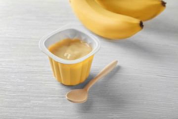 Plastic cup with yummy banana yogurt on wooden table
