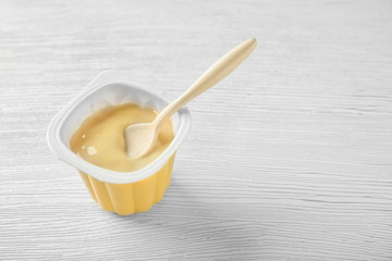 Plastic cup with yummy yogurt on wooden table