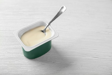 Plastic cup with yummy vanilla yogurt on wooden table
