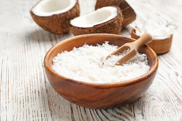 Fresh coconut flakes in bowl on wooden background